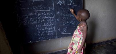 A girl is writing on a black board, in a school in Rwanda. Photo: Simon Rawles/Oxfam