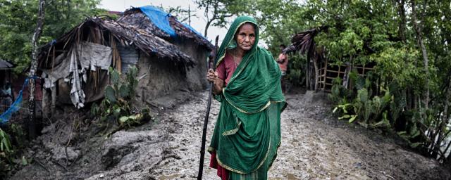 Zohora, 92, walks along a muddy road in Kholpetuya village, searching for food for her grandchildren.