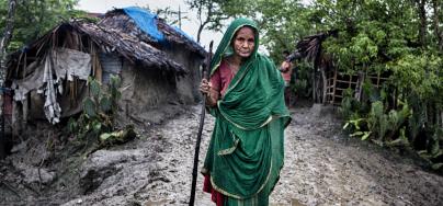 Zohora, 92, walks along a muddy road in Kholpetuya village, searching for food for her grandchildren.