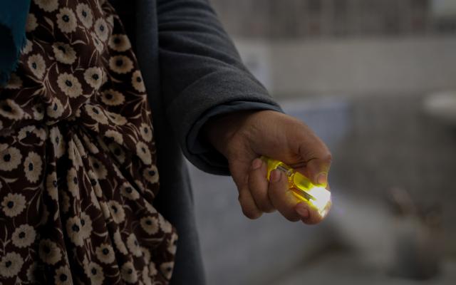 A displaced woman from Aleppo, holds a flashlight she uses to light the way in the corridors. 