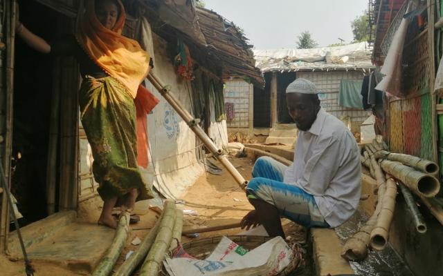 A man and a woman listening to an Oxfam provided bluetooth audio kit in the refugee camp Cox's Bazar