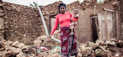 Fatuma walks with her son through her destroyed house after Cyclone Kenneth.