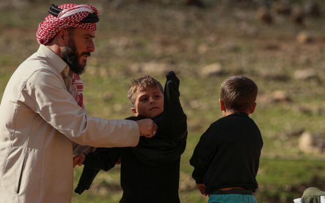 A man and his two young children get winter supplies like blankets and coats from Oxfam to cope with the cold season.