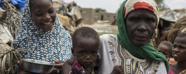 Amina*, 55, a mother of 12, stands with her children outside their hut in the village of Toumour in north eastern Niger, on September 6, 2016. Photo: Pablo Tosco/Oxfam