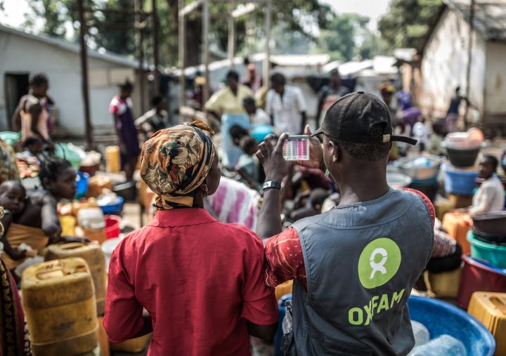 An Oxfam water and sanitation technician with a group of women collecting water at a distribution point built by Oxfam in the displaced camp of Mukassa in Bangui.Credit: Pablo Tosco/Oxfam