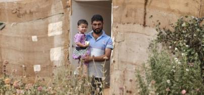 Jemaa Al Halayal, 35, holds his two-year-old daughter Amina, outside the tent in which they now live in an informal settlement for Syrian refugees in north Bekaa Valley in Lebanon on September 10 2015. Photo: Sam Tarling/Oxfam 