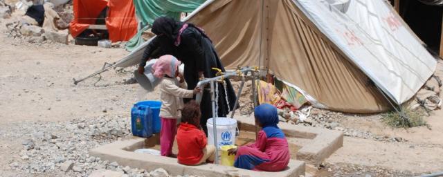 A woman and children gather safe drinking water from the tap Oxfam has installed in Huth IDP camp. Photo: Kate Wiggans/Oxfam