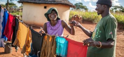 Ulita Mutambo’s husband Muchineripi Sibanda helps her hang up laundry outside their home in Ture Village, Zvishevane region, Zimbabwe.  Credit: d'Unienville/Oxfam