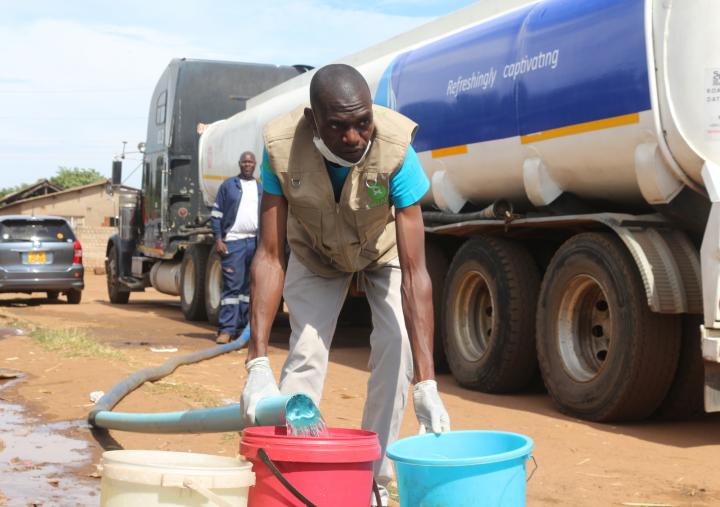 Trust Mugwagwa, Oxfam in Zimbabwe Public Health Engineer, assisting local volunteers to distribute water in Harare suburbs on the 12th of April. 