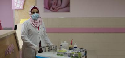 Heba Shalan, a nurse in northern Gaza Strip, wearing a mask and pushing a trolley with medical equipment