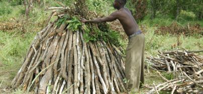 Saibi Mrisho (33) prepares to make charcoal by stacking wood, covering it with leaves and earth and slow burning it over 3 days. Photo credit: Aubrey Wade/Oxfam