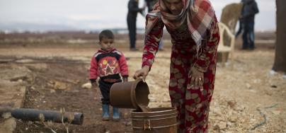 Hannan, 20, disposes of waste water with her son Mohammed*, 2, at an informal settlement for Syrian refugees near the town of Baalbek in Lebanon's Bekaa Valley. Photo: Sam Tarling/Oxfam