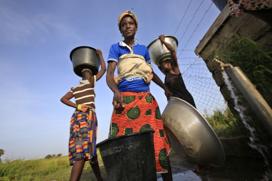 Felicia Ayaawin draws water from the well Oxfam’s partner installed near her home in Kpatua. The well has an electric pump powered by solar panels, and water is stored in a large tank.