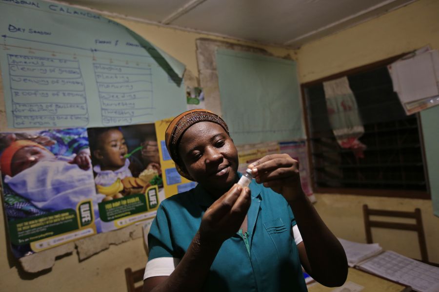 Latana Ganda, the nurse in Kpatua’s clinic, inspects a vaccine she stores in a solar-powered refrigerator. 