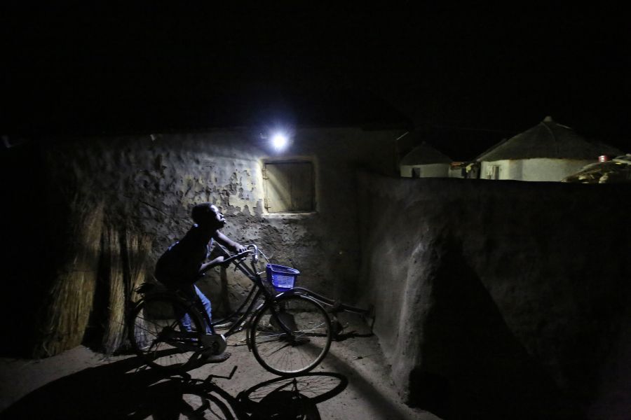 A boy passes by a motion-activated LED light in Kpatua village. The solar energy system at this home generates and stores electricity for night-time use. 