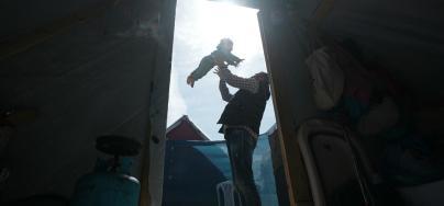 A father plays with his 3-year-daughter in the middle of his tent in Rafah which he took refuge after losing his house and factory.