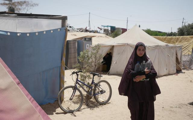 Duaa Abu Sabha holds water bottles while walking to her tent in the Al-Mawasi area in Khan Yunis Governorate.