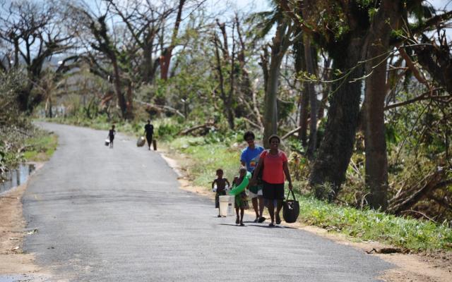 People walking along a road carrying bags