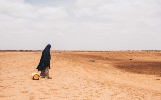 Diyaara, from Wajir County in Kenya, stands before a dried water hole.  